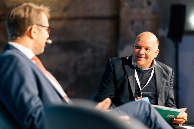 Ein Mann interviewt einen zweiten Mann, beide haben Mikrofon