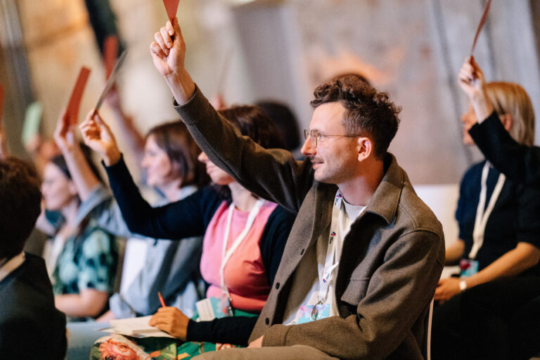 Menschen melden sich auf einer Konferenz und halten rote Karten hoch