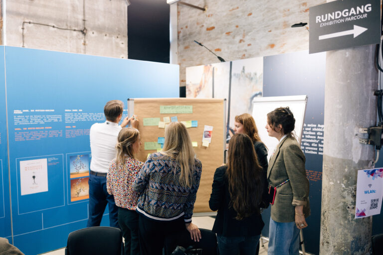 6 Personen arbeiten in einem Workshop an einer Pinnwand